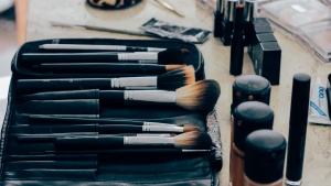 Makeup brushes, powder, lipstick on a table.