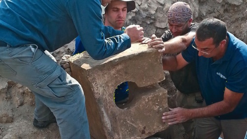 Diggers remove a stone toilet that was used to defile the shrine where the altar was found.