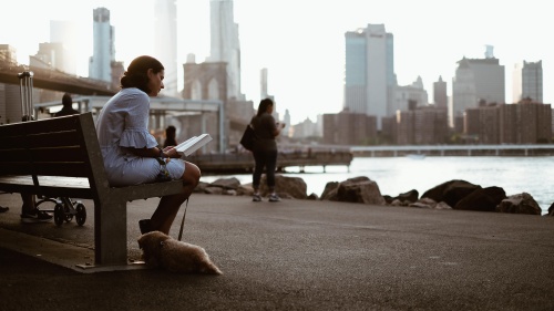 A woman sitting on a bench reading.