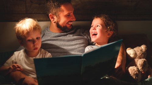 A father reading a book to his kids. 