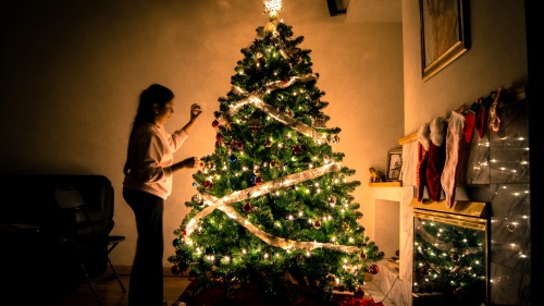 a woman standing in a dark room in front of a glowing Christmas tree